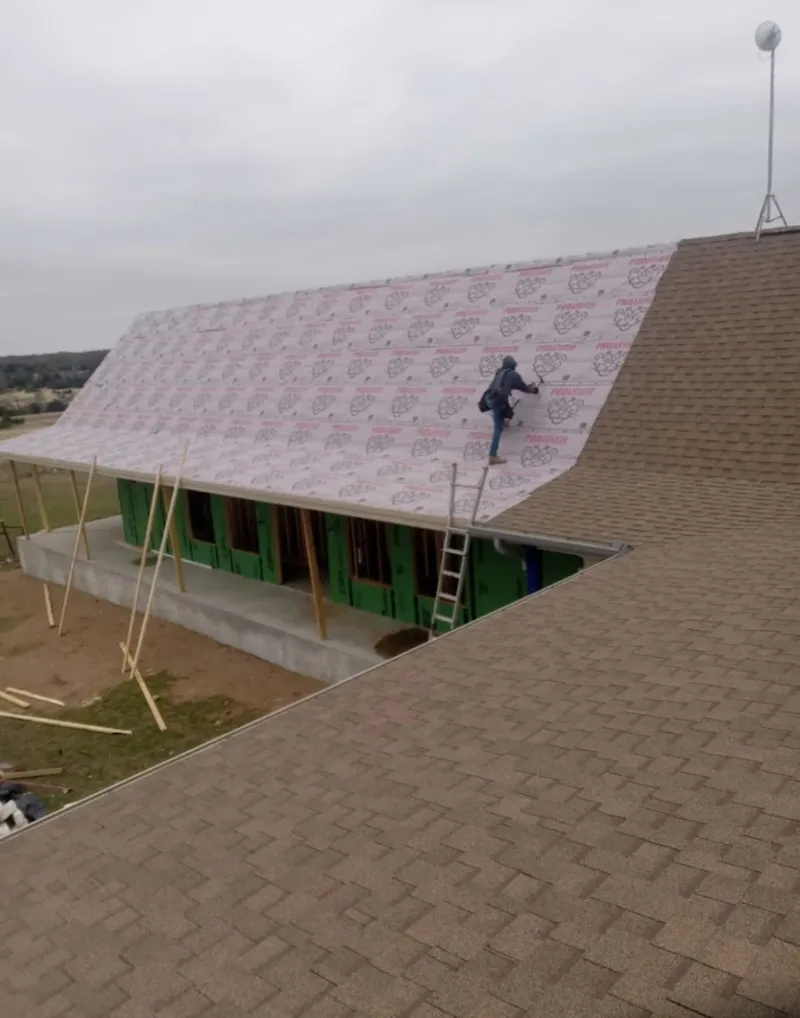 Worker preparing underlayment for a metal roof installation in Ralston